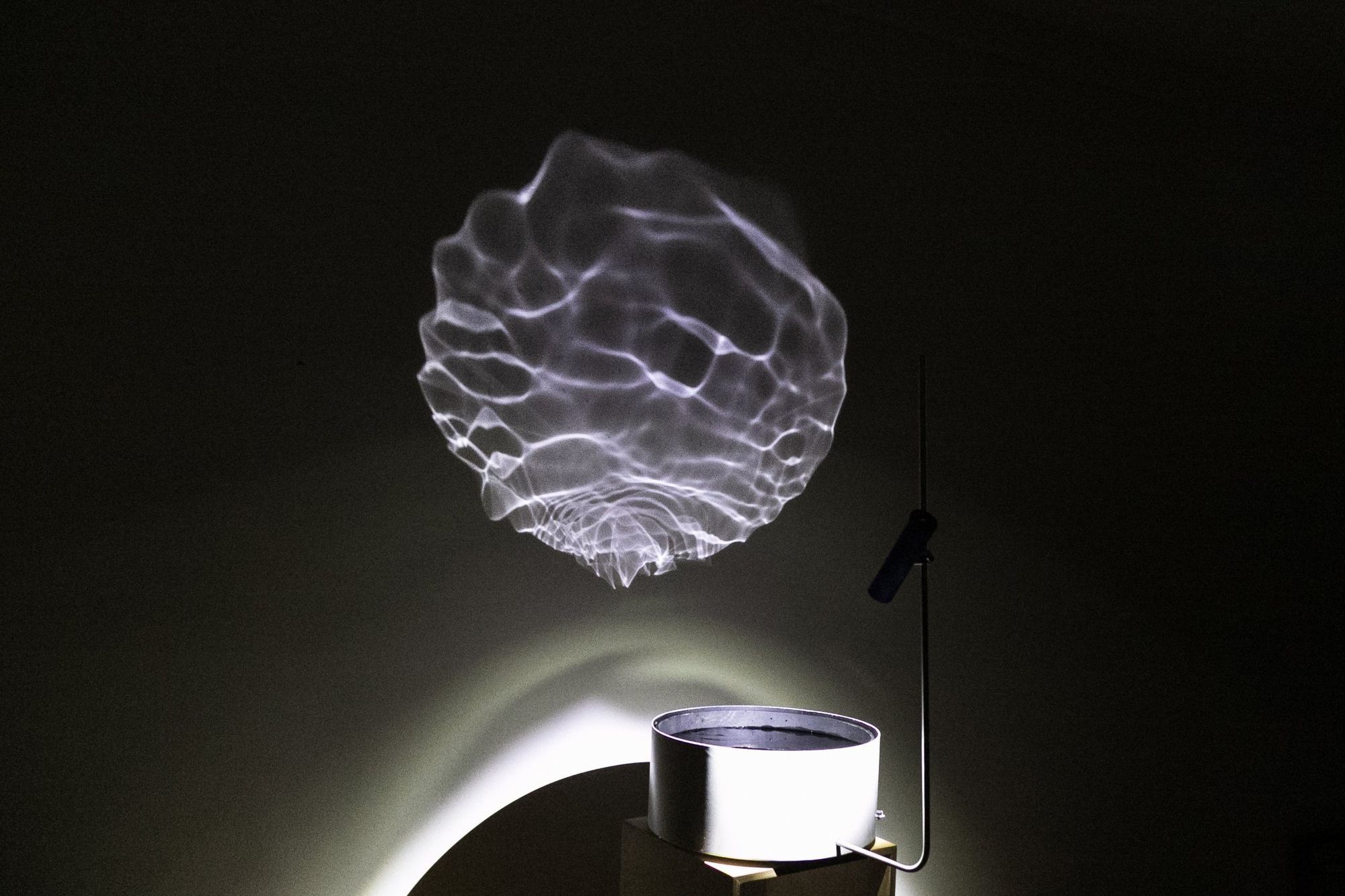 Lichtmuster aus bewegtem Wasser, an eine dunkle Wand projiziert